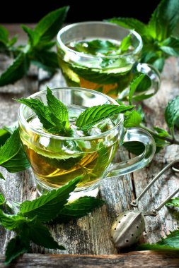 Rustik ahşap arka plan üzerinde cam bardak Taze doğal yeşil pepermint bitkisel çay. Organik aromaterapi gevşeme tıbbi sağlıklı içecek