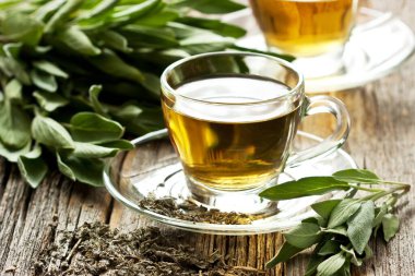 Cam fincanda adaçayı ve ahşap masada adaçayı, sığ alan derinliğinde seçici bir odak