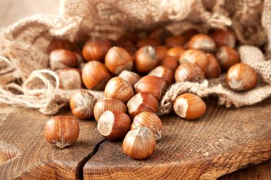 Tahta arka planda çuval içinde fındık. Fındık yığını seçici odak ve sığ alan derinliği 