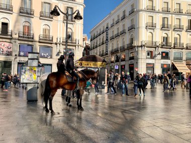 MADRID, İSPAN - Jan 2020. Madrid 'deki Puerta del Sol' da devriye gezen polis. Şehir merkezinde insanlar, mimari ve görkemli bir atla dolup taşıyor..