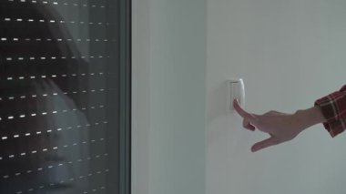 Modern bir evde elektrikli pencere panjurlarını kontrol etmek için düğmeye basmak işe yarar. Akıllı ev otomasyonu, konfor ve enerji verimliliği