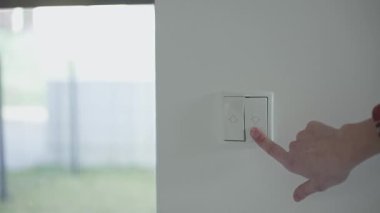 Modern bir evde elektrikli pencereyi kontrol etmek için düğmeye basan kadın panjurları kapatır. Akıllı ev otomasyonu, enerji verimliliği ve günlük hayatta kolaylık