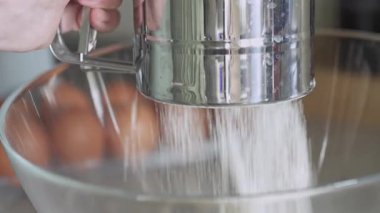 Un, yemek pişirirken metal elek ile cam kaseye karıştırılıyor.