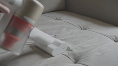 Kablosuz elektrik süpürgesi koltuk yüzeyindeki tozu kaldırıyor.