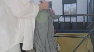 Bahar temizliği sırasında çamaşırları balkonda kurutma askısına koyan bir kadın. Ev işleri ve temizlik kavramı