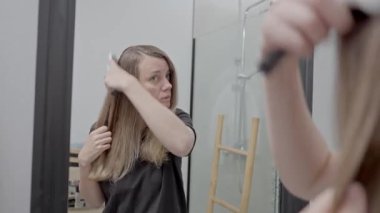 Kadınlar saçlarını banyo aynasının önünde tararlar.