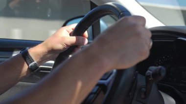 Eller direksiyona tutunarak otoyolda sürerken, görünür iç detayları ve arka planda bir yol manzarası ile