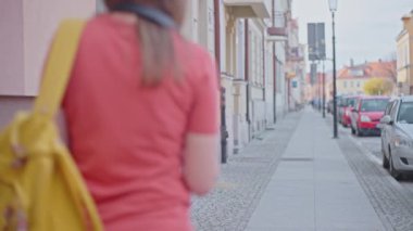 Elinde harita olan ve sarı sırt çantalı bir kadın şehir caddesinde yol tarifi arıyor.