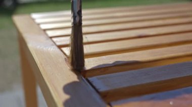 Ağaç yağını bahçe tezgahına sürterek, güneş ışığında yağ parıltısıyla