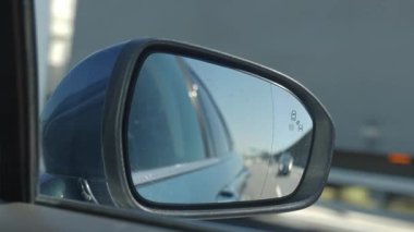 Otoyolda giderken yol ve yakındaki araçları yansıtan bir arabanın yan aynasını kapat.