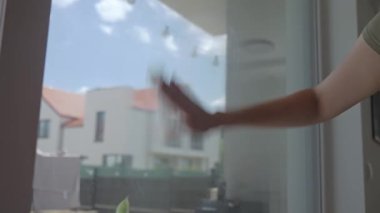 Kadın cam pencereyi içeriden temizliyor. Çamuru temizlemek için bez kullanıyor. Ev temizliği ve ev temizliği kavramı