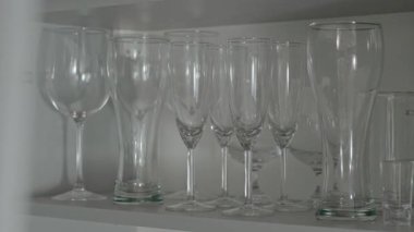 Bir kadının raftan şarap kadehlerini çıkardığı yavaş çekim sahnesi.