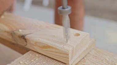 Elektrikli matkap, tezgahın üzerine yerleştirilmiş tahta bir kalasta delik açıyor. Ahşap işçiliği ya da DIY süreci