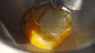 Çiğ yumurtalar paslanmaz çelikten karıştırma kabında çırpılıyor. Pişirme hazırlığı ve tatlı yapma