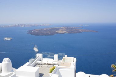 Yunanistan 'ın Santorini kentindeki beyaz turistik bir dairede volkanik ada manzarasında seyahat eden yolcu gemileri ile güzel bir balkon manzarası.