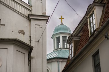 Riga, Letonya 'daki iki yüksek bina arasında altın haçlı güzel bir kilise kulesi.
