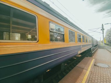 Sarı ve mavi eski tren Riga, Letonya 'da bir tren istasyonunda hareket halinde.