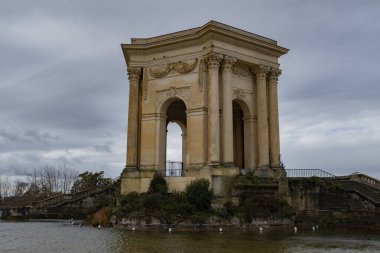 Montpellier 'de bulutlu bir günde güzel bir parkta eski bir taş kemer simgesi.