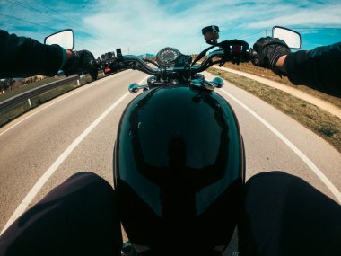 Güneşli bir günde, ikincil asfalt bir yolda siyah yakıt deposu bir motosiklete binmek...