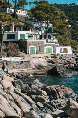 Balıkçının güzel kulübesi kayalık bir kayalık arazide yeşil kapıları olan Akdeniz 'in sakin suları, Costa Brava