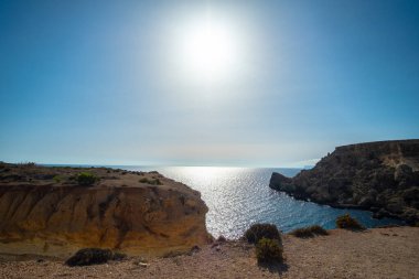 Malta, Mellieha 'da bir sahil koyunda gün batımında güneş gökyüzünde parlıyor.