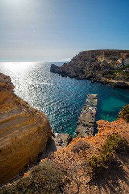 Mellieha, Malta 'da taş iskelesi olan sahil uçurumundaki güzel gün batımı manzarası
