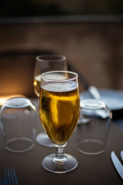 Kahverengi palette servis edilen gümüş sehpanın üzerinde, içki bardağında servis edilen sarışın altın bira.