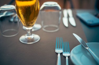 Kahverengi palette servis edilen gümüş sehpanın üzerinde, içki bardağında servis edilen sarışın altın bira.