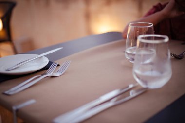Gümüş çatal bıçak takımı sipariş edilmiş ve kahverengi bir palette bir restoranda servis edilmiş.