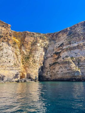 Malta Adası 'ndaki sakin Akdeniz sularında kıyı kayaları üzerinde kayalık oluşumu