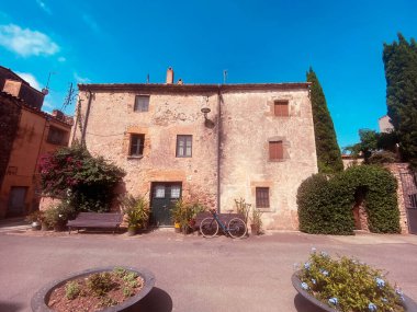 Girona, Katalonya 'da güzel bir kasabada eski bir çiftlik evinin önüne park edilmiş mavi bisiklet.