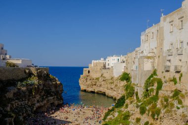 Beautiful cliff beach in Mediterranean Sea in the town of Polignano, south Italy summer holidays scene clipart