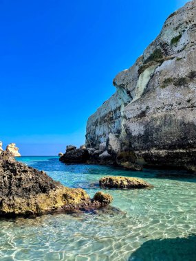 Puglia, İtalya 'da mavi bir Akdeniz' de turkuaz sessiz sularla kayalık uçurumu