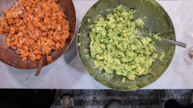 İki kâse avokado ve portakallı somon, restoranın mutfağında doğranmış.