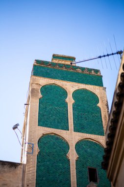 Fas 'ın Fez kentindeki Bou Inania Medersa' nın Arap tarzı eski bir binasının güzel yeşil kulesi.