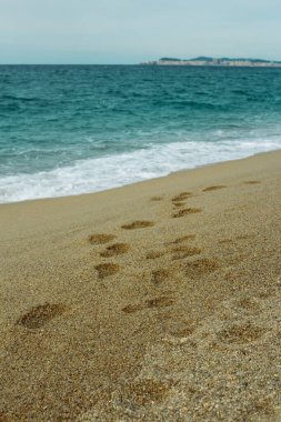 Costa Brava 'da sakin suları olan bir sahilde kumsalda ayak sesleri.