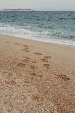 Costa Brava 'da sakin suları olan bir sahilde kumsalda ayak sesleri.