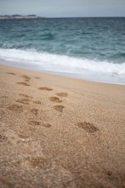 Akdeniz 'de sakin suları olan kumlu bir sahilde ayak sesleri.