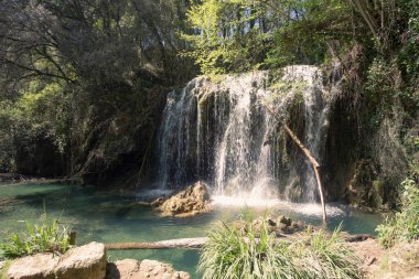 Girona 'da bir ormandaki turkuaz bir nehirde akan güzel şelale.
