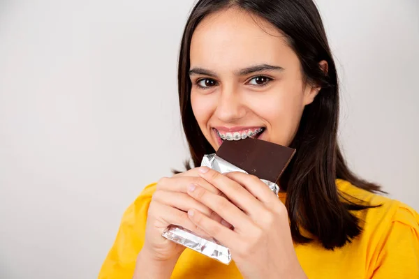 Menina Adolescente Bonita Com Ortodontia Metal Mordendo Uma Barra Chocolate — Fotografia de Stock
