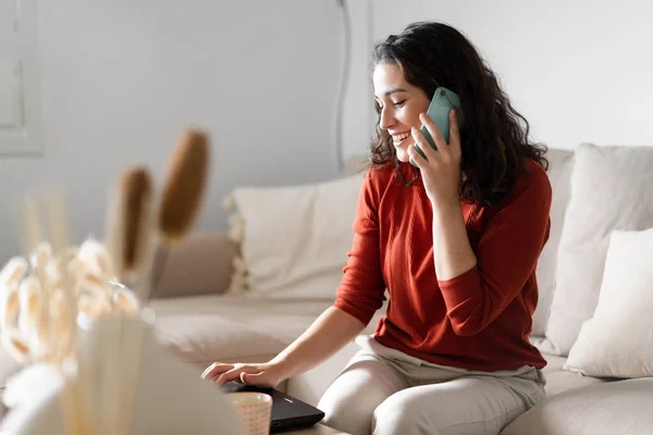 Jovem Mulher Feliz Falando Telefone Digitando Computador Sentado Sofá Casa — Fotografia de Stock