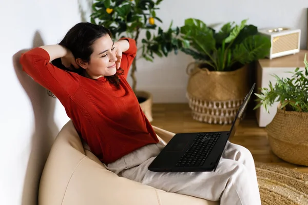 Relaxed Young Woman Sitting Bag Chair Stretched Arms Using Laptop — Stock Photo, Image