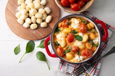 Kremalı domates soslu gnocchi güveci bebek ıspanaklı ve ahşap masa üzerine erimiş mozzarella. Üst görünüm