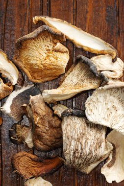 Kurutulmuş gurme mantarlar kırsal bir ahşap masanın üzerine serilmiştir. Sağlıklı beslenme ürünü.