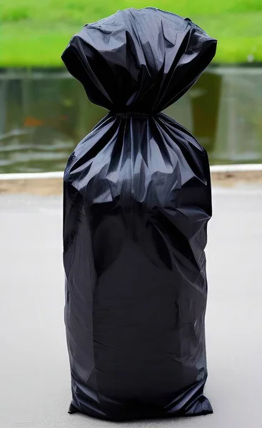 a closeup shot of a black plastic bag with a garbage on a white background
