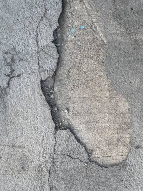 Kırık beton bir duvarın fotoğrafı. Üzerinde mavi bir sopa var. Duvarda çatlaklar ve çatlaklar var.