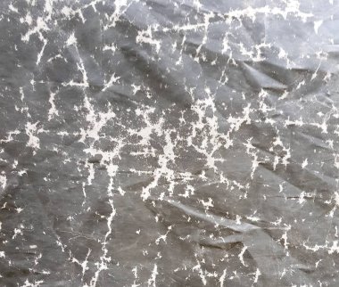 Kirli bir duvarın siyah beyaz bir fotoğrafı. Üzerinde saat olan kirli bir duvarın yakın çekimi var.