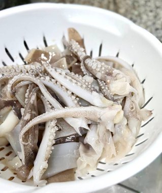 Masada bir kase mürekkep balığı ve soğan resmi var. Masada bir kase mürekkep balığı ve diğer yiyecekler var.