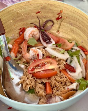 İçinde karides, domates ve mürekkep balığı olan bir kase şehriye, karides, domates ve kalamar.