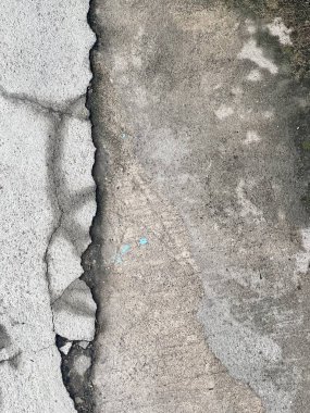 Kaldırımdaki kırık bir yangın musluğunun fotografı. Üzerinde çatlaklar ve çatlaklar olan beton bir duvar.